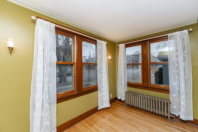 interior space with crown molding, radiator, baseboards, and light wood-style floors