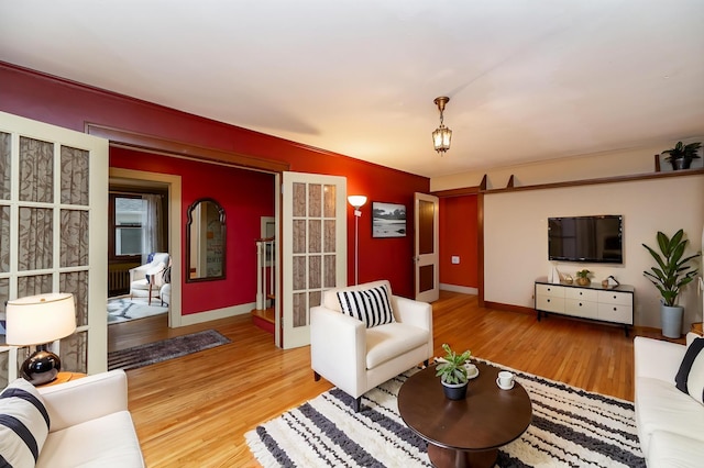 living area with french doors, baseboards, and wood finished floors