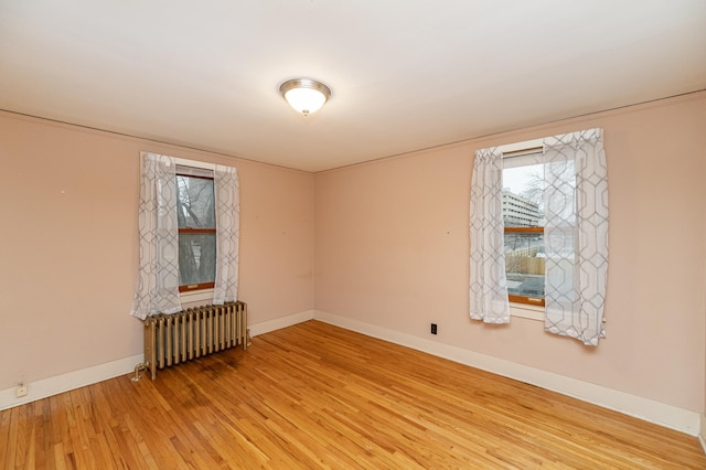 spare room with radiator heating unit, baseboards, and wood finished floors