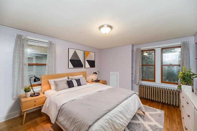 bedroom featuring radiator heating unit and light wood-style flooring