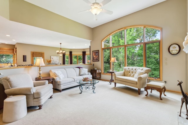 carpeted living room with recessed lighting, baseboards, a sink, and ceiling fan with notable chandelier