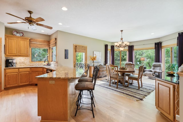 kitchen featuring a breakfast bar, a peninsula, tasteful backsplash, and light wood finished floors