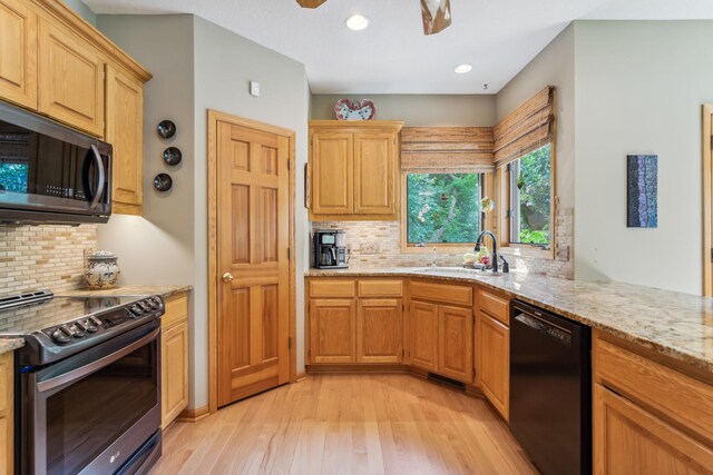 kitchen featuring light stone counters, light wood-style flooring, a sink, electric stove, and black dishwasher