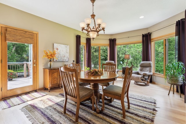 dining space with a wealth of natural light, light wood-type flooring, and an inviting chandelier