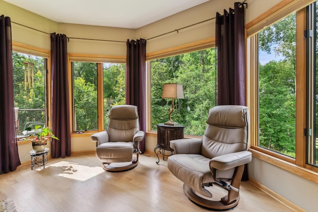 sitting room with plenty of natural light, wood finished floors, and baseboards