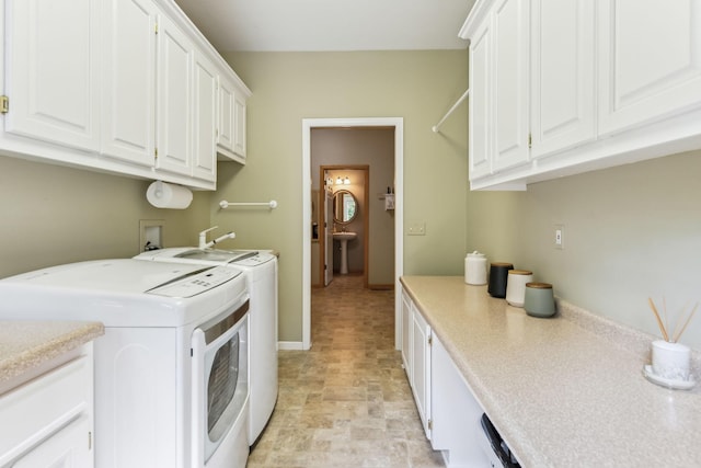 laundry room featuring washing machine and clothes dryer, baseboards, stone finish floor, cabinet space, and a sink