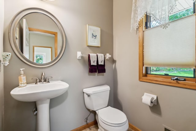 half bathroom with a sink, baseboards, and toilet