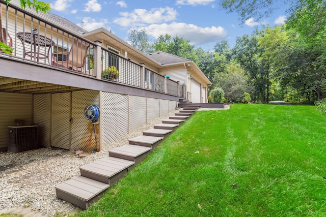 view of yard with central air condition unit, a garage, a wooden deck, and stairway