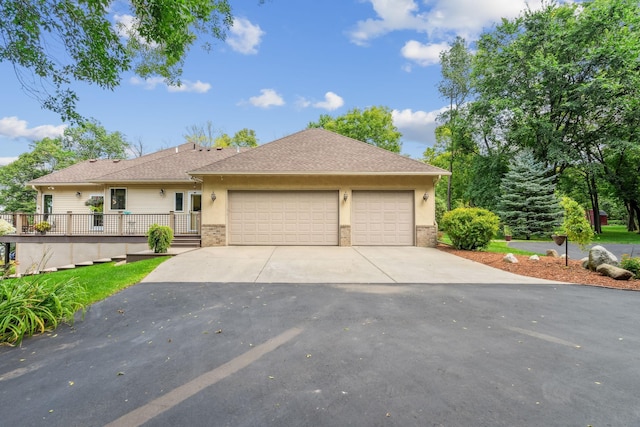 ranch-style home featuring stucco siding, roof with shingles, concrete driveway, an attached garage, and brick siding