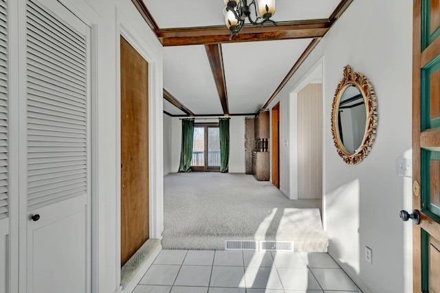 hall featuring a notable chandelier, beam ceiling, light colored carpet, and light tile patterned flooring