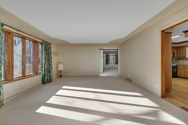 empty room with crown molding, visible vents, and a baseboard radiator