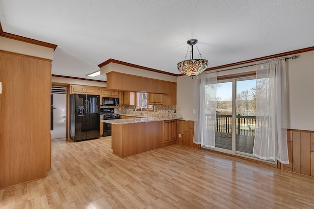 kitchen featuring backsplash, ornamental molding, light wood-style flooring, a peninsula, and black appliances