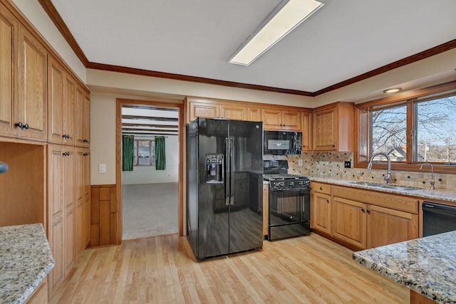 kitchen featuring light stone counters, plenty of natural light, black appliances, and a sink