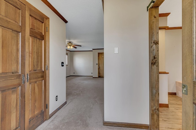 hallway with crown molding, baseboards, and light carpet