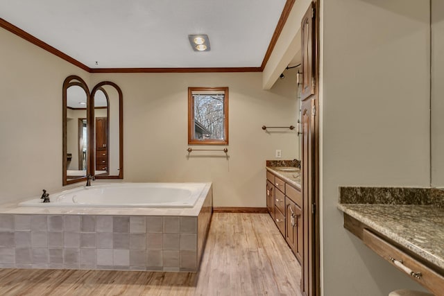 full bath with wood finished floors, crown molding, baseboards, a bath, and vanity