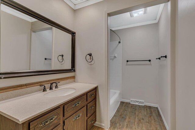 bathroom featuring visible vents, wood finished floors, ornamental molding, and vanity