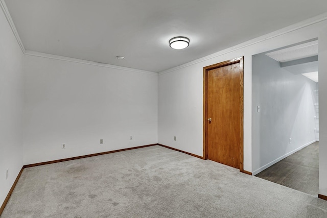 carpeted spare room with crown molding and baseboards