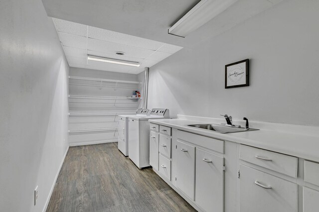 kitchen featuring a sink, washing machine and dryer, dark wood finished floors, white cabinets, and light countertops