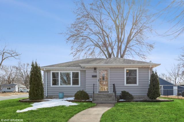 bungalow featuring a shingled roof, a front lawn, and fence