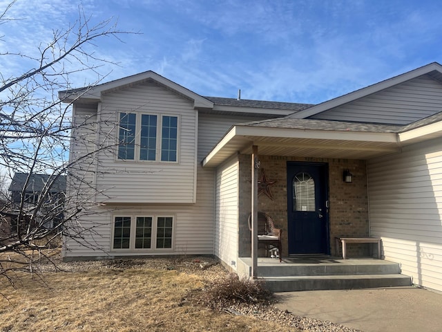 doorway to property with brick siding and a shingled roof