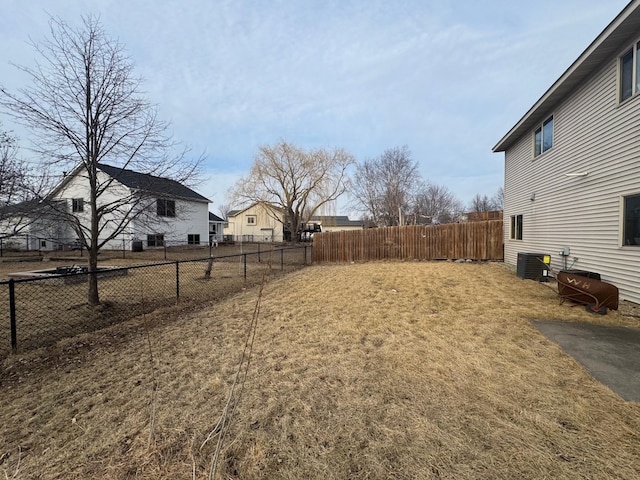 view of yard featuring central AC and fence