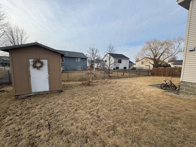 view of yard featuring a residential view, an outdoor structure, a fenced backyard, and a storage shed