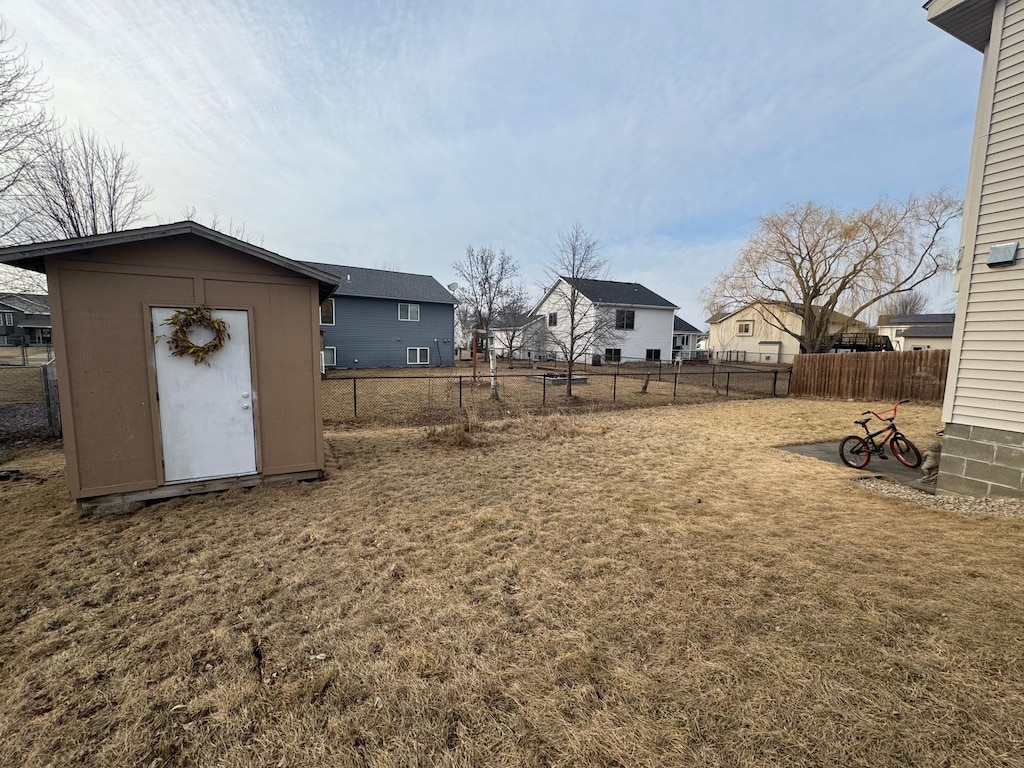 view of yard with a residential view, an outdoor structure, a storage shed, and a fenced backyard