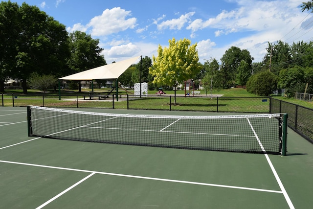 view of tennis court featuring fence and playground community