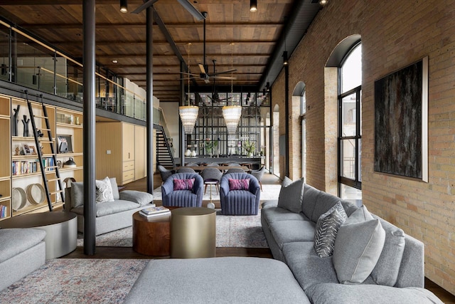 living area with stairway, ceiling fan, brick wall, and a towering ceiling