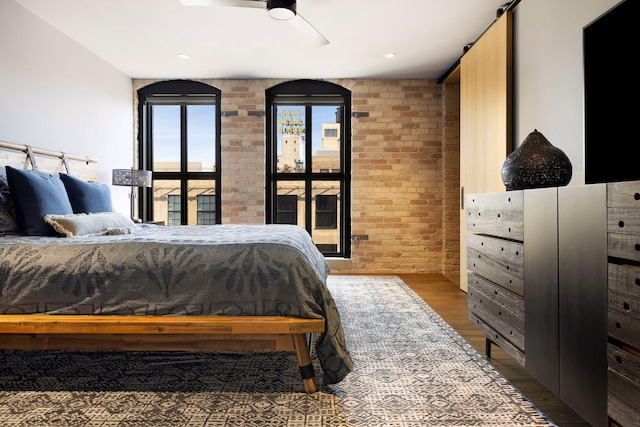 bedroom with brick wall, a ceiling fan, and wood finished floors