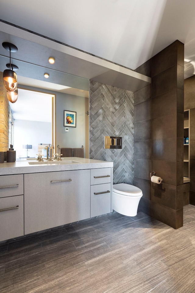 bathroom with vanity, tile walls, and toilet