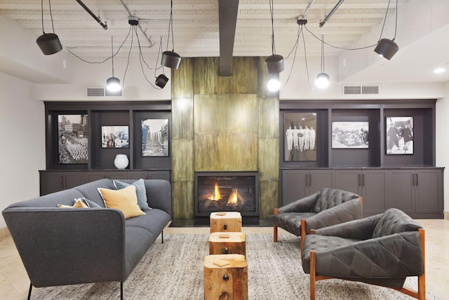 living room featuring a tiled fireplace, beam ceiling, and visible vents