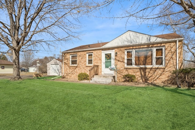 single story home featuring an outdoor structure, a front yard, a shingled roof, a garage, and brick siding