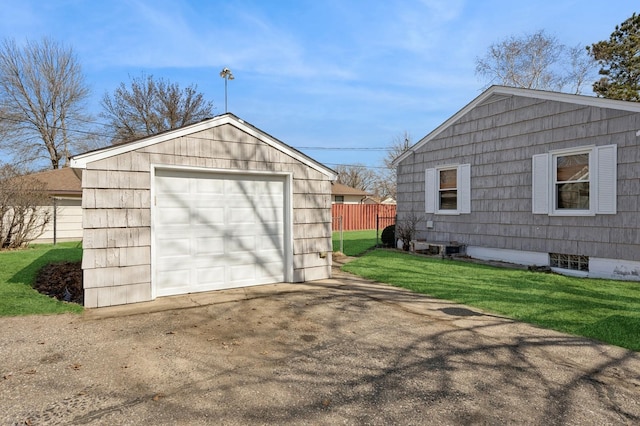 detached garage featuring concrete driveway and fence