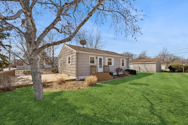 rear view of property with an outdoor structure, a lawn, and fence