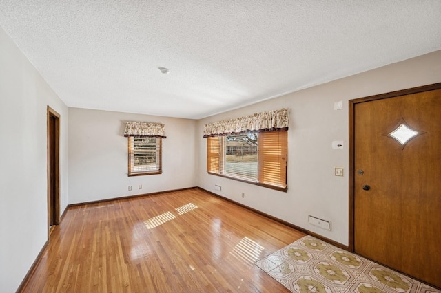 entrance foyer featuring light wood-style flooring, baseboards, and a textured ceiling