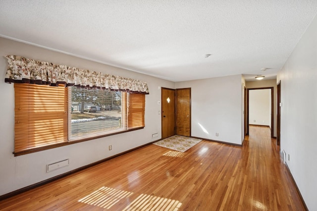 unfurnished room with wood finished floors, baseboards, and a textured ceiling