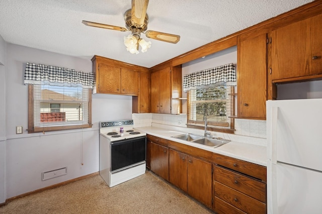 kitchen featuring light countertops, brown cabinetry, white appliances, a textured ceiling, and a sink