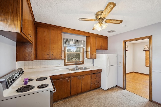 kitchen with visible vents, brown cabinets, white appliances, and a sink