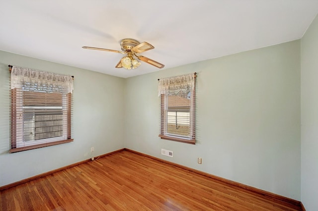 empty room featuring visible vents, baseboards, a ceiling fan, and wood finished floors