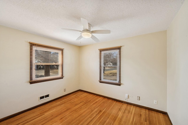 spare room with a wealth of natural light, visible vents, baseboards, and light wood-style flooring