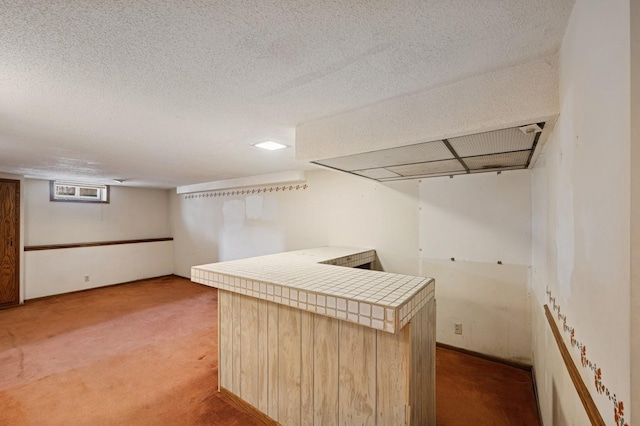 basement with light carpet, a bar, and a textured ceiling