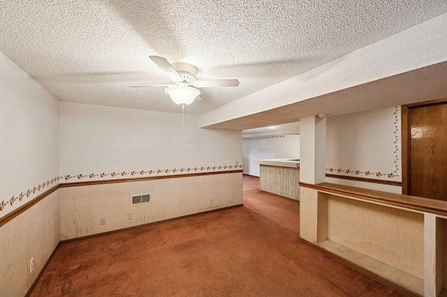 carpeted spare room with a ceiling fan, visible vents, and a textured ceiling