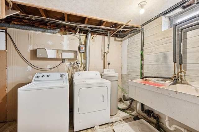 washroom with washer and dryer, laundry area, wooden walls, and a sink