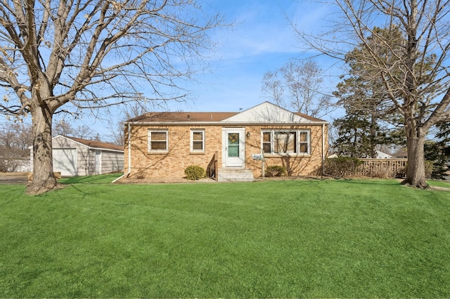 back of house featuring a lawn, an outdoor structure, and brick siding