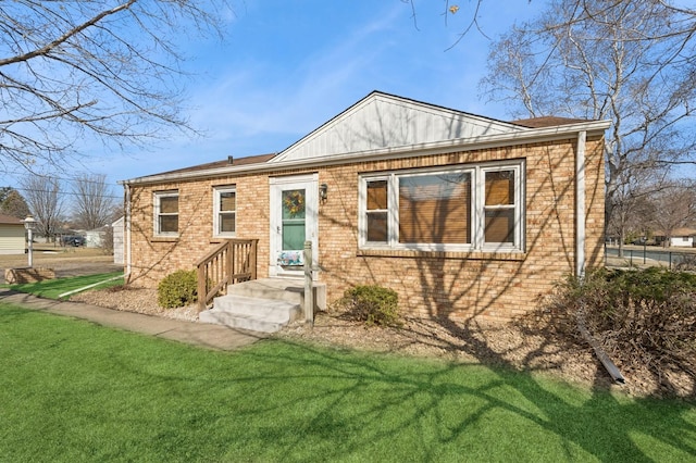 back of property with a lawn and brick siding