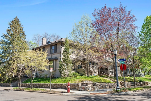 view of front of property featuring a chimney, stucco siding, and stairs