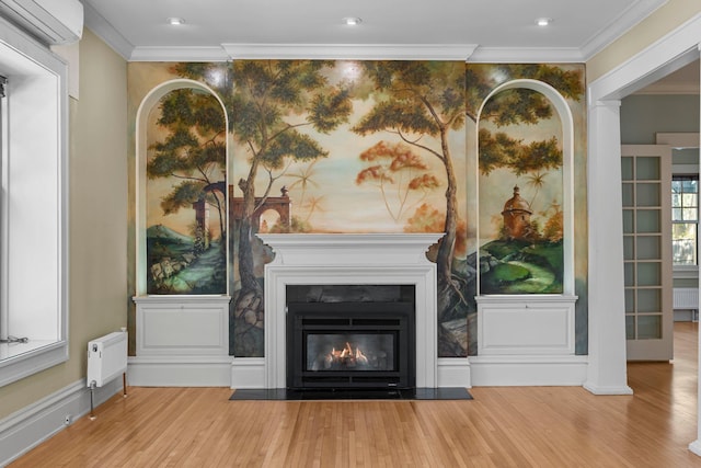 unfurnished living room with wood finished floors, a wall mounted AC, crown molding, a glass covered fireplace, and radiator