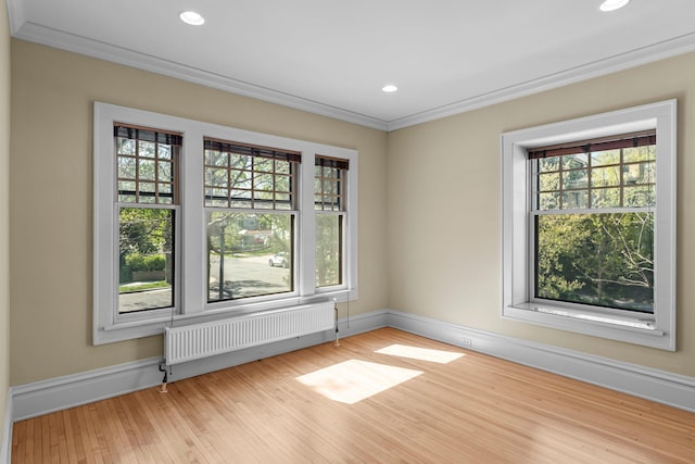 unfurnished room with radiator heating unit, crown molding, baseboards, wood finished floors, and recessed lighting