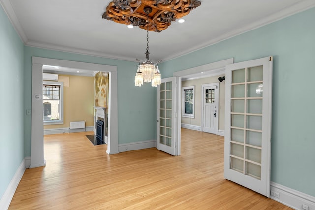 unfurnished dining area featuring a chandelier, crown molding, light wood-type flooring, a fireplace with flush hearth, and baseboards
